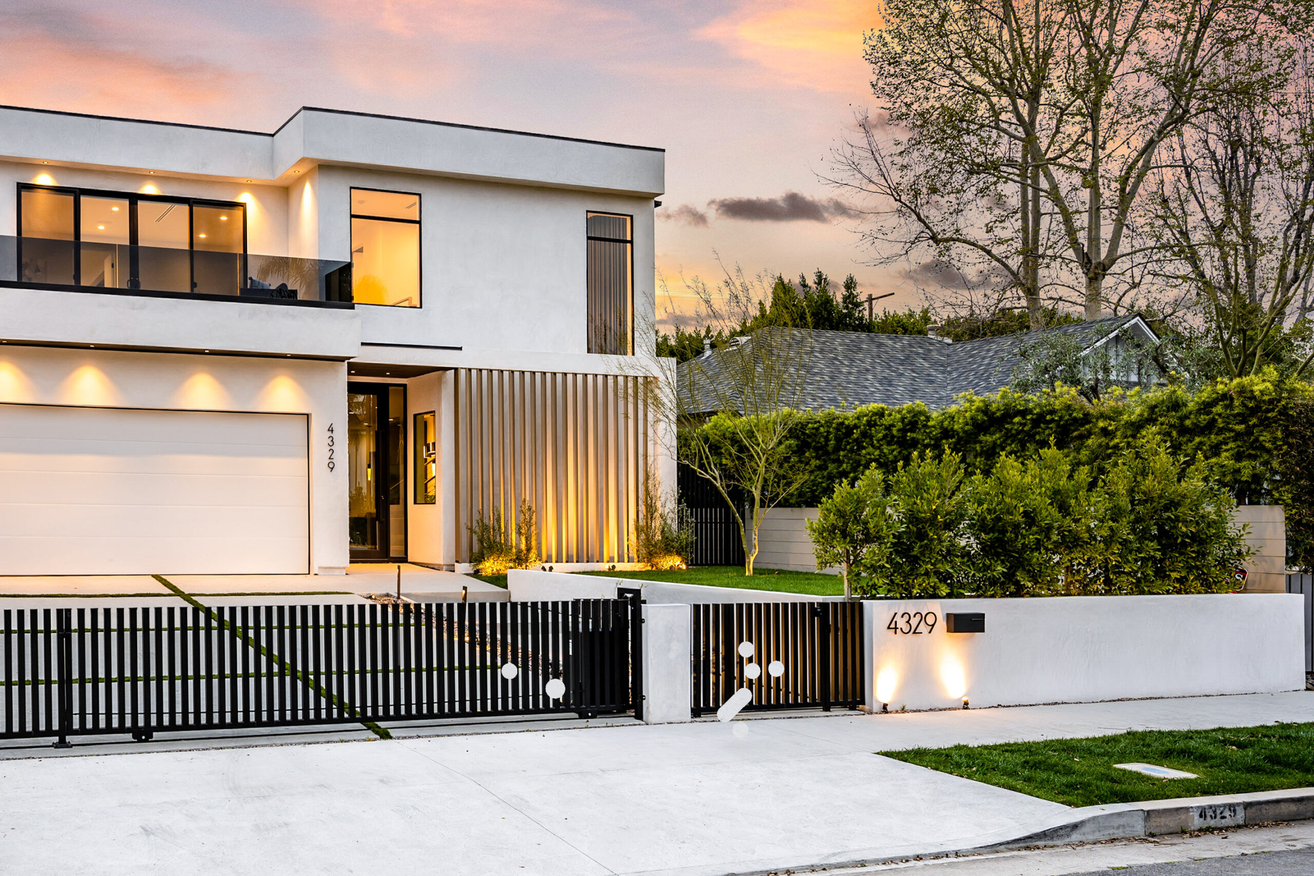 A large white house with a charming gate surrounded by trees
